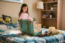Adorabile poco asiatico ragazza imballaggio valigia su letto — Foto stock