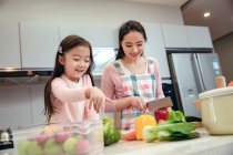 Felice giovane madre asiatica e adorabile piccola figlia cucinare insieme in cucina — Foto stock