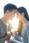 Vista laterale di felice giovane coppia che tiene gli occhiali di latte a casa — Foto stock