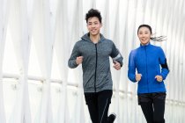 Lächelnde junge asiatische Läufer, die gemeinsam im Freien trainieren — Stockfoto