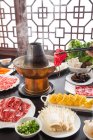 Cropped shot of person holding chopsticks with meat above copper hot pot, chafing dish concept — Stock Photo