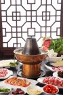 Nahaufnahme von Essstäbchen mit Fleisch über Kupfer-Hotpot, Scheuern Teller-Konzept — Stockfoto
