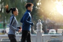 Side view of smiling young asian runners training together outdoor in the morning — Stock Photo