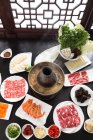 Hochwinkelblick auf Teller mit verschiedenen Zutaten und Kupfer-Hot-Pot, Scheuern Gericht Konzept — Stockfoto