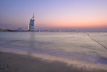 Dubai, Emirati Arabi Uniti - 10 ottobre 2016: L'illuminato Burj Al Arab hotel e marina al tramonto, vista dalla spiaggia di Jumeira, guardando a sud-ovest . — Foto stock