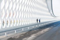 Vista completa de la joven deportista y deportista corriendo juntos en el puente moderno - foto de stock