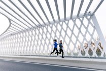 Pleine longueur vue de jeune asiatique couple courir ensemble sur pont — Photo de stock