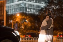 Счастливая азиатская пара обнимается на улице вечером — стоковое фото