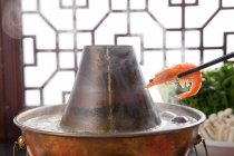 Vista close-up de pauzinhos com camarão acima de cobre panela quente, conceito prato de atrito — Fotografia de Stock