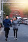 Young male and female athletes in sportswear running together on street — Stock Photo