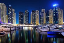 Incroyable célèbre port de plaisance de Dubaï avec des yachts et des gratte-ciel reflétés dans l'eau la nuit — Photo de stock