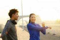 Jovem asiático homem e mulher no sportswear alongamento durante o treino na ponte na manhã — Fotografia de Stock
