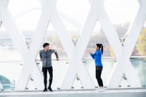 Athletic young couple in sportswear training together on bridge — Stock Photo