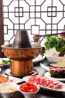 Copper hot pot, meat, vegetables and seafood on table, chafing dish concept — Stock Photo