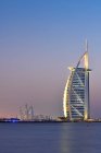 Dubái, Emiratos Árabes Unidos - 10 de octubre de 2016: El iluminado hotel y puerto deportivo Burj Al Arab al atardecer, vista desde la playa de Jumeirah, mirando al suroeste . - foto de stock