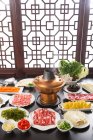 Vista de ángulo alto de varios ingredientes, carne, verduras, mariscos y olla caliente de cobre, concepto de plato de roce - foto de stock