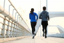 Back view of couple of joggers running together on bridge — Stock Photo