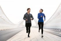 Молоді чоловіки і жінки-спортсмени посміхаються один одному і бігають разом — стокове фото