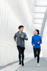 Jovem casal esportivo sorrindo uns aos outros e correndo juntos na ponte — Fotografia de Stock