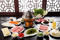 Copper hot pot with meat and vegetables on table, chafing dish concept — Stock Photo