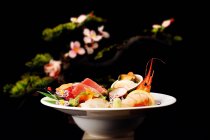 Крупный план вкусной японской кухни с блюдами из морепродуктов, подаваемых на белой тарелке — стоковое фото
