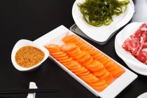 Close-up view of delicious hot pot dishes on white plates on black surface — Stock Photo