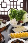 Chaudron de cuivre, herbes, maïs et champignons sur des assiettes, concept de plat de frottement — Photo de stock