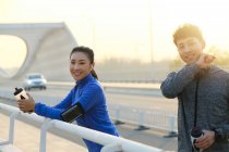 Молоді азіатські спортсмени тримають пляшки води і посміхаються на камеру після тренування на вулиці — стокове фото