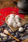 Traditionelle chinesische klebrige Reisbällchen auf Weidengefäß, Teekanne und Löffel mit Sesam — Stockfoto