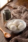 Klebrige Reisbällchen in Schüssel, Holzlöffel und Sesam auf dem Tisch — Stockfoto