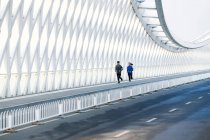 Giovane coppia di joggers in abbigliamento sportivo formazione insieme sul ponte — Foto stock