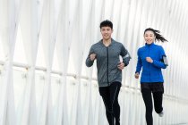 Feliz jovem asiático casal no sportswear correndo juntos na ponte — Fotografia de Stock