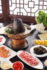 Copper hot pot, meat, vegetables and seafood on table, chafing dish concept — Stock Photo