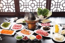 High angle view of various ingredients, meat, vegetables, seafood and copper hot pot, chafing dish concept — Stock Photo
