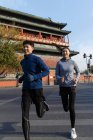 Усміхнені молоді чоловіки і жінки спортсмени бігають разом вулицею — стокове фото