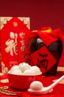 Boules de riz gluantes dans un bol et des cartons rouges avec des caractères chinois dorés — Photo de stock