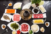 Vista superior de varios ingredientes, carne, verduras, mariscos y olla caliente de cobre, concepto de plato de roce - foto de stock