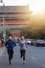 Улыбающиеся молодые спортсмены и спортсмены, бегущие вместе по улице — стоковое фото