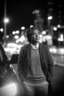 Schwarz-Weiß-Foto von nachdenklichen reifen asiatischen Mann in der Nähe von Auto stehen und wegschauen in der Nacht Stadt — Stockfoto