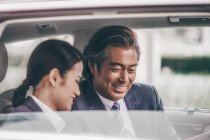 Sorrindo asiático negócios pessoas sentado no carro — Fotografia de Stock