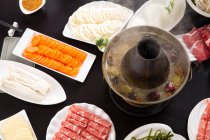 Vista superior de la olla caliente de cobre, verduras y carne en la mesa, concepto de plato de roce - foto de stock
