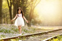 Adorable asian kid walking on railroad at sunny evening — Stock Photo