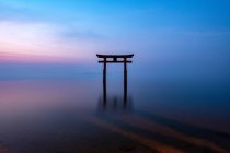 Torii en el lago Biwa con un santuario durante el amanecer - foto de stock