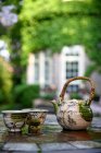 Close-up view of ceramic tea set with kettle and cups on table in backyard — Stock Photo