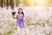 Adorável asiático criança no vestido andando com buquê de flores no campo — Fotografia de Stock