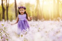 Adorable asiático niño en vestido caminar con flor corona en campo - foto de stock