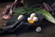 Vista de cerca de huevos crudos y cebolla sobre una mesa de madera - foto de stock