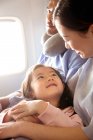 Glückliche Familie mit einem Kind, das mit dem Flugzeug reist, Mädchen schaut Mutter an — Stockfoto