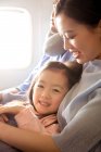 Glückliche Familie mit einem Kind, das mit dem Flugzeug reist, Mädchen lächelt in die Kamera — Stockfoto