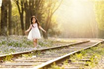 Adorable asian kid walking on railroad at sunny evening — Stock Photo